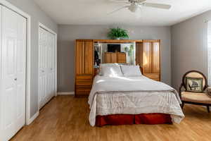 Bedroom featuring ceiling fan, light hardwood / wood-style floors, and two closets