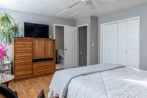 Bedroom with ceiling fan, a closet, ensuite bathroom, and light hardwood / wood-style flooring