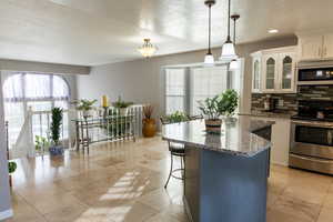 Kitchen featuring white cabinets, decorative light fixtures, stainless steel appliances, and a healthy amount of sunlight