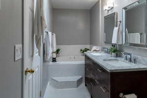 Bathroom featuring tile patterned flooring, vanity, and tiled bath