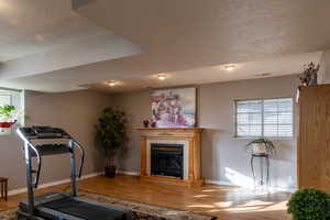 Exercise room with a textured ceiling and hardwood / wood-style flooring