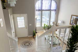 Entrance foyer with a healthy amount of sunlight, light tile patterned flooring, and a chandelier