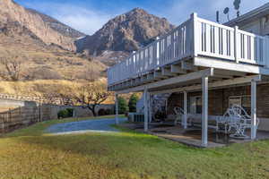 View of yard with central AC unit, a deck with mountain view, and a patio