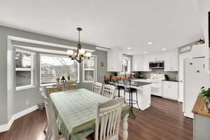 Dining area with dark hardwood / wood-style flooring, plenty of natural light, and a notable chandelier