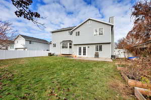 Rear view of house with a lawn, a patio area, and french doors