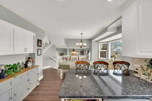 Kitchen with a chandelier, white cabinets, dark wood-type flooring, and decorative light fixtures