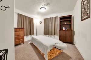 Bedroom with light carpet and a textured ceiling