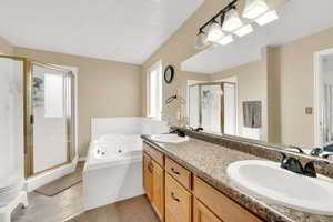 Master Bathroom featuring vanity, separate shower and tub, and a textured ceiling