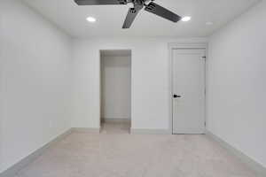 Unfurnished bedroom with ceiling fan and light colored carpet