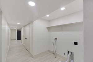 Basement Laundry Roomfeaturing electric dryer hookup, washer hookup, and light hardwood / wood-style floors