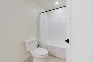 Basement Bathroom 2 featuring shower / bathtub combination with curtain, wood-type flooring, and toilet