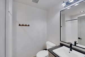 Bathroom featuring a shower, vanity, and toilet