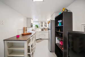 Kitchen featuring white cabinets, stainless steel refrigerator, and sink