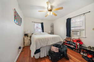 Bedroom featuring hardwood / wood-style flooring, ceiling fan, and cooling unit