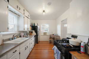 Kitchen featuring white cabinets, gas stove, plenty of natural light, and sink