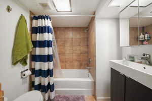 Full bathroom featuring shower / bath combination with curtain, vanity, and toilet