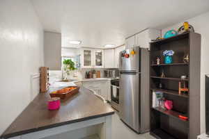 Kitchen with white cabinets, stainless steel appliances, kitchen peninsula, and sink