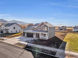 View of front of home with a mountain view, a garage, covered porch, and a front yard