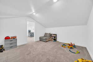 Recreation room featuring light colored carpet and lofted ceiling