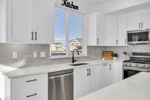 Kitchen with white cabinets, backsplash, sink, and stainless steel appliances