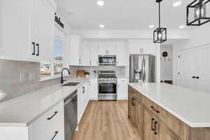 Kitchen with a center island, stainless steel appliances, white cabinetry, and sink