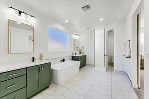 Bathroom featuring vanity, toilet, and a tub to relax in