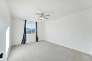 Carpeted empty room featuring ceiling fan