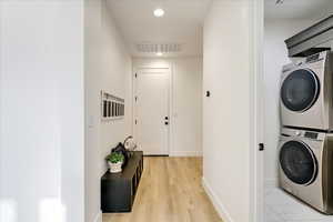 Washroom featuring light hardwood / wood-style flooring and stacked washer / drying machine