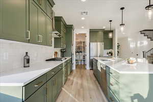 Kitchen featuring sink, light hardwood / wood-style flooring, decorative light fixtures, and green cabinetry