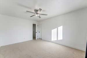 Carpeted empty room featuring ceiling fan