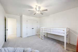 Carpeted bedroom featuring a closet and ceiling fan