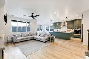 Living room featuring light wood-type flooring, ceiling fan, and sink