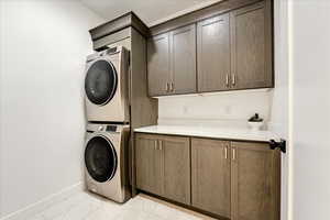 Clothes washing area with cabinets and stacked washing maching and dryer