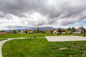View of home's community featuring a mountain view, a yard, and basketball hoop