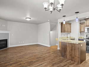 Kitchen with sink, dark wood-type flooring, kitchen peninsula, pendant lighting, and electric stove