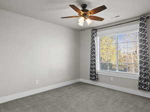 Empty room with carpet flooring, ceiling fan, and a healthy amount of sunlight