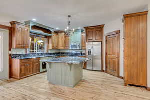 Kitchen with light wood-type flooring, a kitchen breakfast bar, a center island, and stainless steel appliances