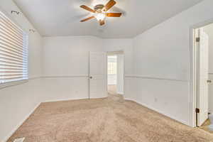 Spare room featuring ceiling fan, lofted ceiling, and light carpet