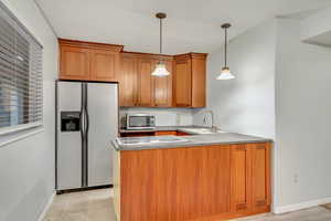 Kitchen with kitchen peninsula, sink, pendant lighting, and appliances with stainless steel finishes