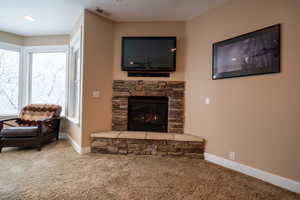 Living room featuring a fireplace, carpet, and a healthy amount of sunlight