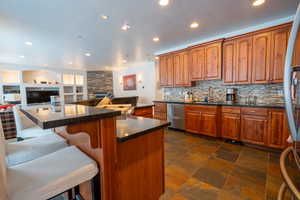 Kitchen featuring a breakfast bar, a center island, a stone fireplace, sink, and tasteful backsplash