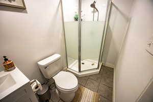 Bathroom featuring tile patterned floors, sink, an enclosed shower, and toilet