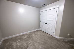 Unfurnished bedroom featuring carpet, a textured ceiling, and a closet