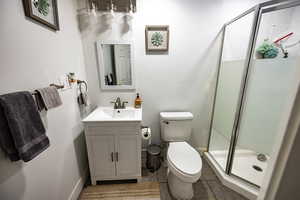 Bathroom with tile patterned floors, vanity, an enclosed shower, and toilet