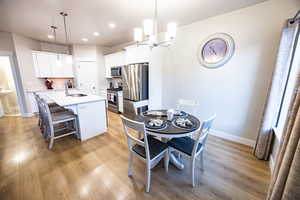 Dining space featuring a notable chandelier, light wood-type flooring, and sink