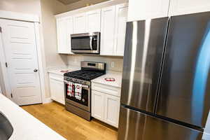 Kitchen featuring white cabinets, stainless steel appliances, and light hardwood / wood-style floors