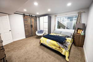 Carpeted bedroom featuring a barn door