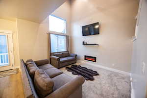 Living room with light wood-type flooring and a towering ceiling