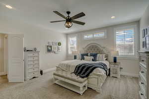 Carpeted bedroom featuring ceiling fan and multiple windows