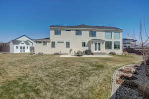 Back of property with a yard, a patio, french doors, and a storage unit